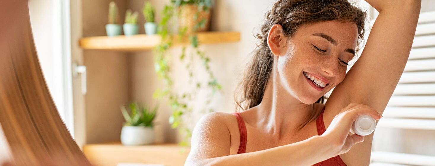 Person smiling applying deodorant