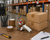 Peppergrass tan packing tape sealing cardboard boxes with dispenser in warehouse shipping environment
