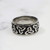 Two Tone Triquetra stainless steel ring with raised Trinity Knot design on black background.