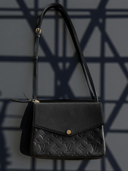 Louis Vuitton Black Monogram Empreinte Crossbody Bag front view hanging in black leather, flap close & gold button close