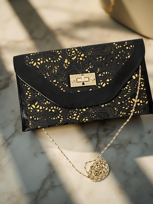 Front view black laser-cut clutch with gold underlay, envelope flap & turn-lock closure,  with gold chain strap