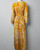 Charlie Irish Yellow Maxi Dress with Slit full back view showing fabric drape, bow tied belt & white leaf print