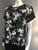 Edition Black Short Sleeve Floral Top angled front showing soft fabric, relaxed cut, hemline & cuffed sleeve detail