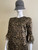 Michael Kors Gold Metallic Lace Mini Dress angled front with round neck, fitted bodice & fluffy paisley lace on sleeve