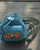 Moschino Turquoise Quilted Mini Backpack front view on wood deck & intertwined leather & gold chain straps on the side