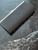New Look Black Textured Clutch angled top view without the chain showing gold-tone trim frame on black surface