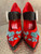 Prada Red Satin Mary Jane Heels front view of wide black strap & intricate blue beading on front of the pointed toes