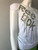 Reebok White Short Sleeve Top – angled side view showing gold Reebok graphic & sleeve unclipped with exposed shoulder cut-out
