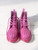 Dr. Martens Pink Spike Boots front view with lace-up front, rounded toes & spike detailing across both boots