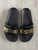 Moschino Gold Logo Slides top view with black wide strap, oversized gold-tone MOSCHINO logo & moulded black footbed