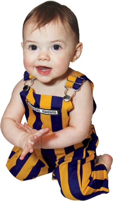 A baby wearing a purple & yellow infant game bib overalls.