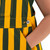 Close-up of green and yellow youth Game Bibs overalls showing side pocket, striped fabric and metal Game Bibs button.