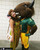 A woman wearing striped green & gold game bib overalls posing with a Bison mascot.