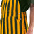 Detail shot of the side button closures and waist pockets on green and gold striped Game Bibs overalls.