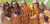 Five women wearing striped maroon & gold game bibs in a football stadium.