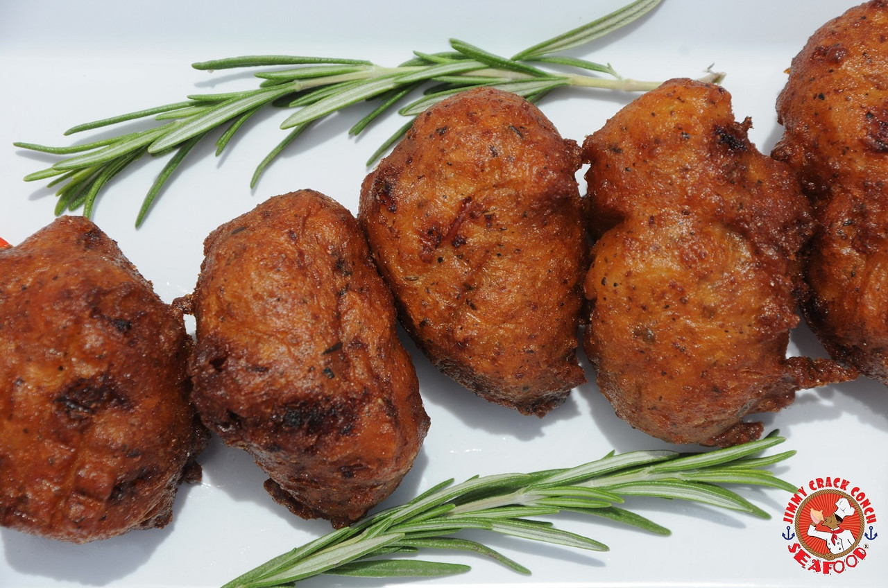 conch fritters on a white plate with thyme sprigs