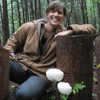A woman next to a log fruiting lion's mane mushrooms.