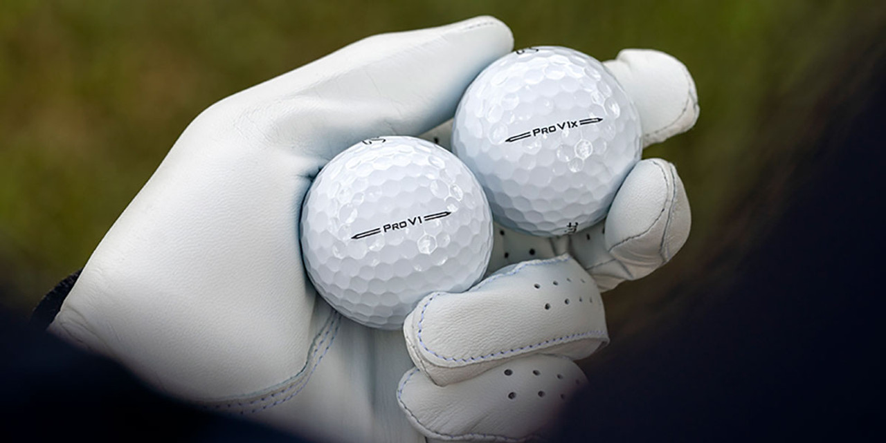 A gloved hand holding Titleist Pro V1 & Pro V1x golf balls
