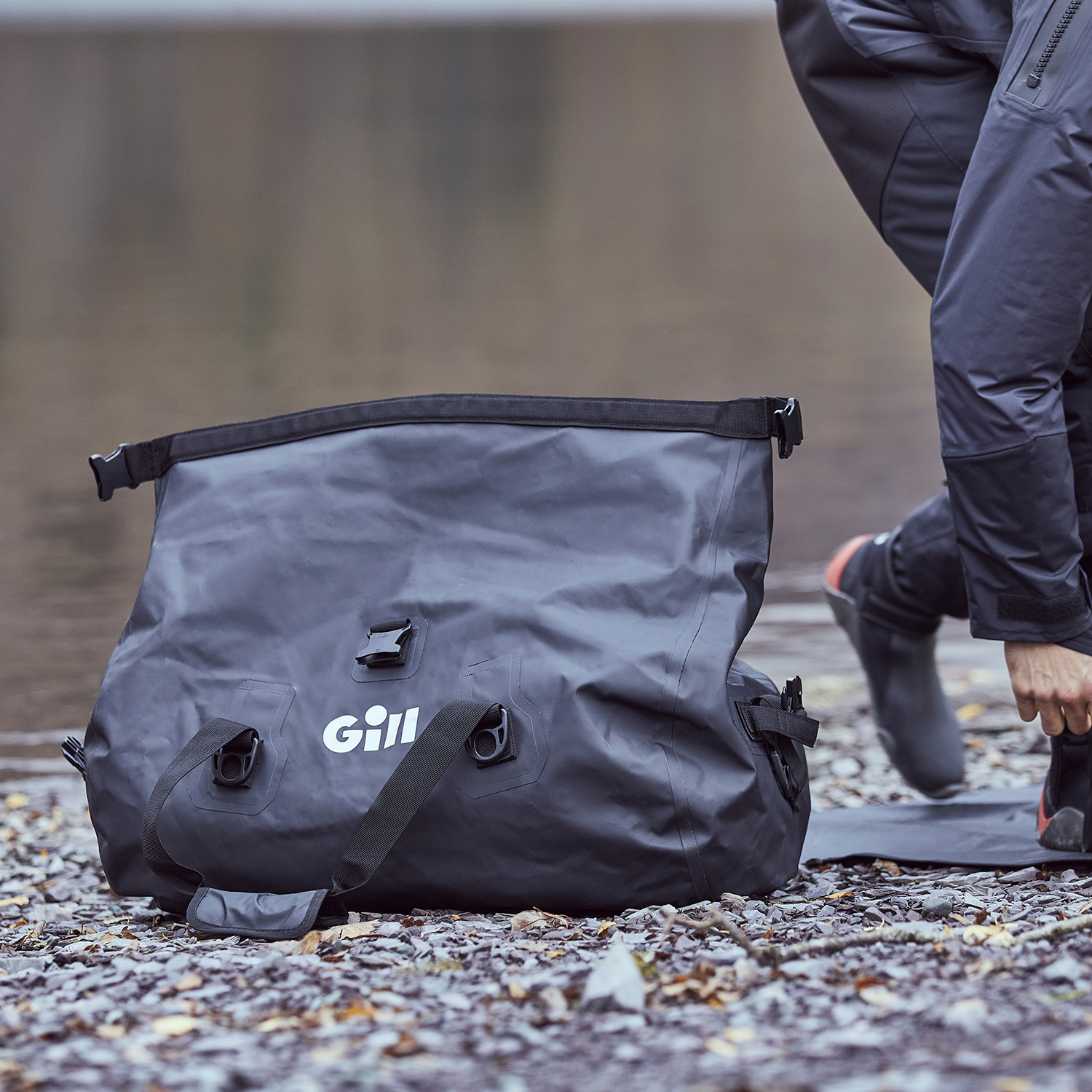 A Gill Voyager Duffel Bag sat open on the stones next to the lake