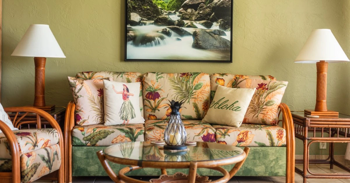A tropical living room has a rattan furniture set. The sofa and armchair are upholstered in a tropical floral print.