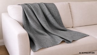 AI simulation of gray textured upholstery fabric draped across a white sofa, highlighting the fabric's woven texture, soft drape, and natural folds in a neutral residential interior. The image is a digital visualization created from an actual fabric photograph and is intended to demonstrate color, pattern, and general appearance.