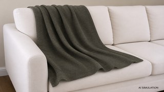 AI simulation of fabric draped over a cream upholstered sofa, featuring an olive-charcoal textured woven fabric with realistic folds, natural drape, and a studio-style interior presentation. The image includes an AI SIMULATION label in the lower-right corner. The image is a digital visualization created from an actual fabric photograph and is intended to demonstrate color, pattern, and general appearance.