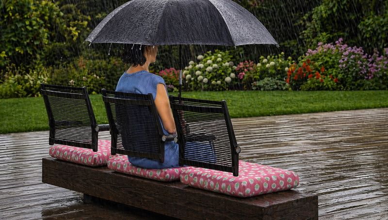 Outdoor performance upholstery fabric by the yard shown on bench cushions in a rainy garden setting