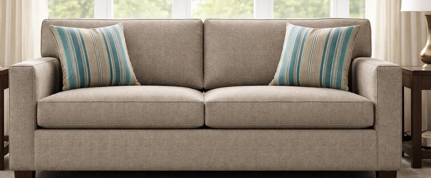 Elegant living room with a taupe upholstered sofa and striped accent pillows, representing Richloom upholstery fabric and coordinating patterns.