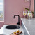 Modern matte black kitchen mixer tap by Meir installed on a white stone benchtop in a contemporary Australian home interior.