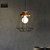 Industrial black cage pendant light fixture with geometric metal frame and wood accents for modern Australian home interiors.