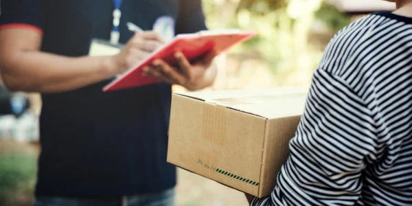 Driver assessing item checks on clipboard during box delivery