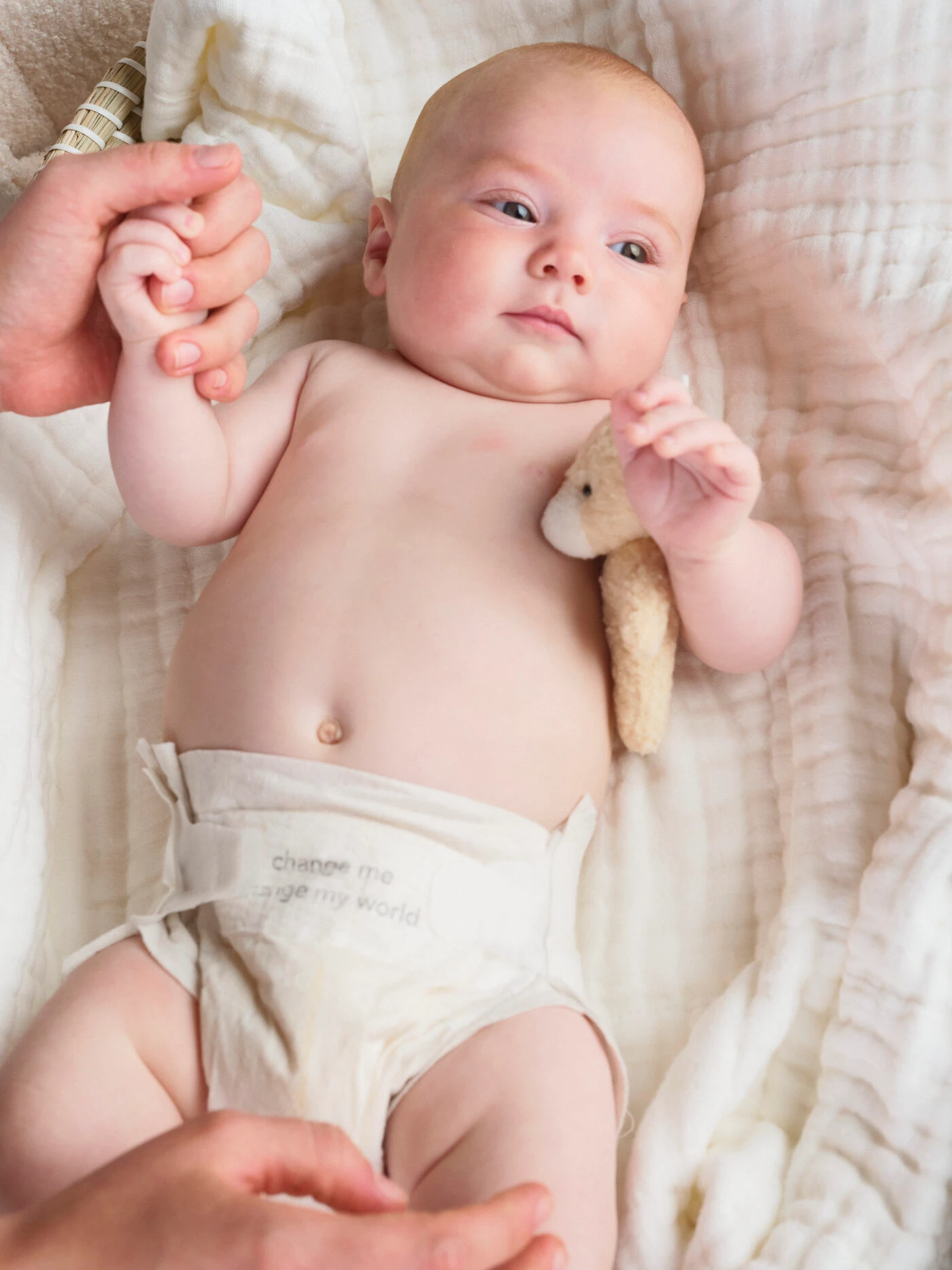 Baby wearing a change cotton diaper, held gently on soft cotton