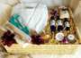 Large husk basket filled with white robe, gel eye mask, pumice stone brush, and blue bottles of bath and body products