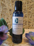 Massage body oil in a blue Blissful Balance bottle with purple silk flowers