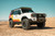 Front right view of an LC250 in the dessert sand with mods including KC HiLites on the roof rack. Front right view of an LC250 in the dessert sand with mods including KC HiLites on the roof rack.