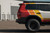 A side view of a Toyota Land Cruiser with an orange and yellow wrap, sitting in front of a warehouse building. A side view of a Toyota Land Cruiser with an orange and yellow wrap, sitting in front of a warehouse building.