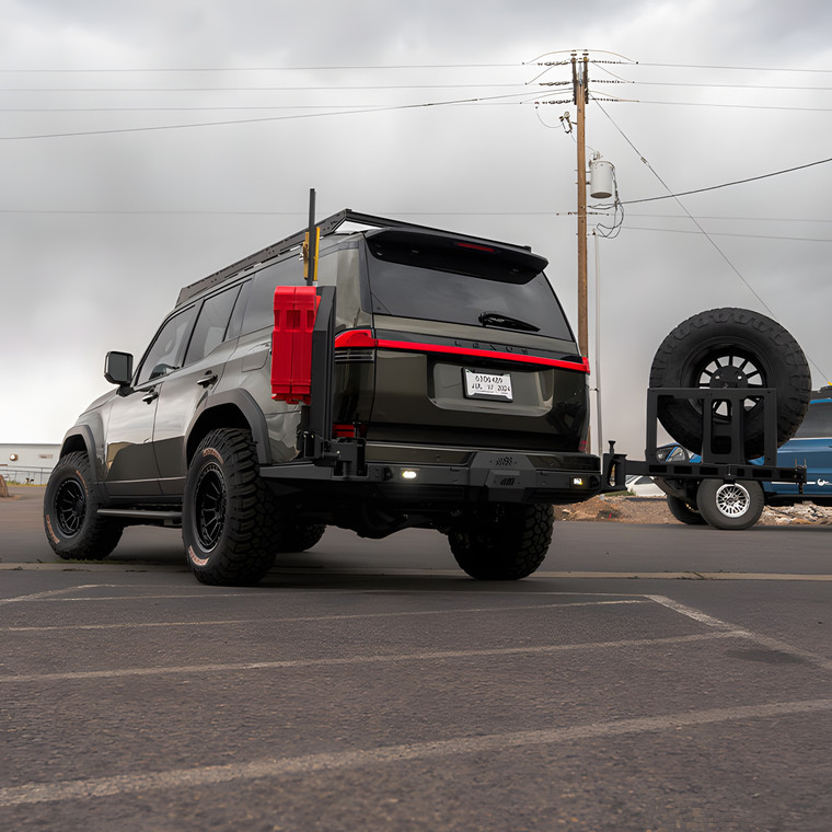 A green Lexus GX550 with aftermarket wheels, tires, bumpers, and a CBI rear swing arm kit to mount the spare tire.