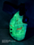 Dual-layer OWB holster with Car Town Carpet fabric wrap over a glow-in-the-dark green outside layer, photographed in darkness to demonstrate the illuminated outer layer beneath the wrap.