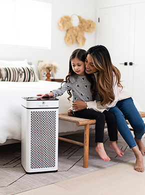 Mother and child adjusting the air purifier sitting on the floor