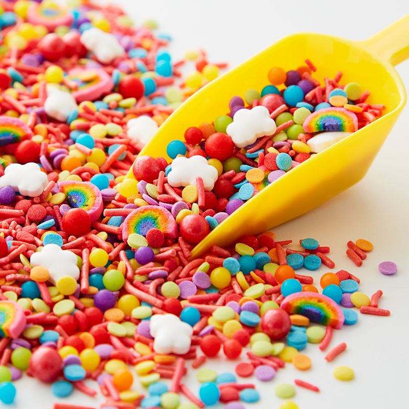 Pile of assorted sprinkles with a yellow scooper ready to pick some up.