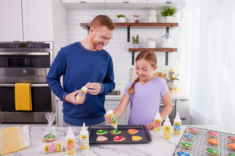 Father and daughter decorating cookies with Wilton's ready-to-use cookie icing bottles.