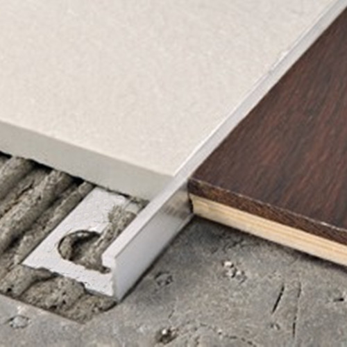 Straight edge tile trim for for creating uncoupling joints between floor sections in similar or different materials.