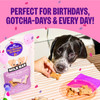 An e-commerce lifestyle graphic for Wellness Old Mother Hubbard Milk Bar dog biscuits set against a pink header with confetti. The image shows a close-up lifestyle photograph of a black-and-white dog on a striped tablecloth being fed a bone-shaped treat by hand, right next to a standing pouch of "P'nutty B-Day Party" biscuits and a clear plate filled with more treats. Bold purple text at the top reads, "PERFECT FOR BIRTHDAYS, GOTCHA-DAYS & EVERY DAY!"