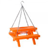 Product photograph of a miniature wooden picnic table designed as a hanging squirrel or bird feeder, set against a solid white background. The picnic table is painted bright orange and features a main tabletop with two attached bench seats on either side. A clear plastic feeding cup is recessed into a circular cutout in the center of the tabletop, and a vertical metal nail is placed on the bench structure to hold food items like corn cobs. The feeder hangs from a silver metal S-hook connected to a three-pronged silver chain attached to the four corners of the table's benches.