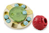 A front product photograph showcasing an interactive pet enrichment toy set isolated against a white background. The set includes a circular cream-colored puzzle toy with a translucent green spinning center, light blue paw-print sliders, and yellow flip lids, positioned next to a textured red rubber treat-dispensing ball.