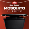 Close-up promotional graphic for Ortho Home Defense Mosquito Kill & Prevent. The image shows the upper half of a black plastic mosquito trap station set against a dark red background, with the glowing white product logo text positioned prominently above it.