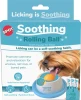 A product box for the SPOT Soothing Rolling Ball Broth Feeder for dogs featuring a small dog licking an orange roller ball set inside a blue and white feeder base, with three chicken broth packets shown on the side, isolated on a white background.