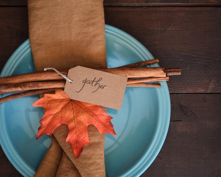 Fall table setting with cinnamon sticks, a fall leaf, and blue plate