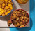 Overhead view of Pecan CaramelCrisp and Garrett Mix in bowls in a summery picnic setting