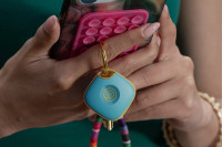 A person holding their phone and keys with a Life360 Tile - Aqua Lemon attached to it.